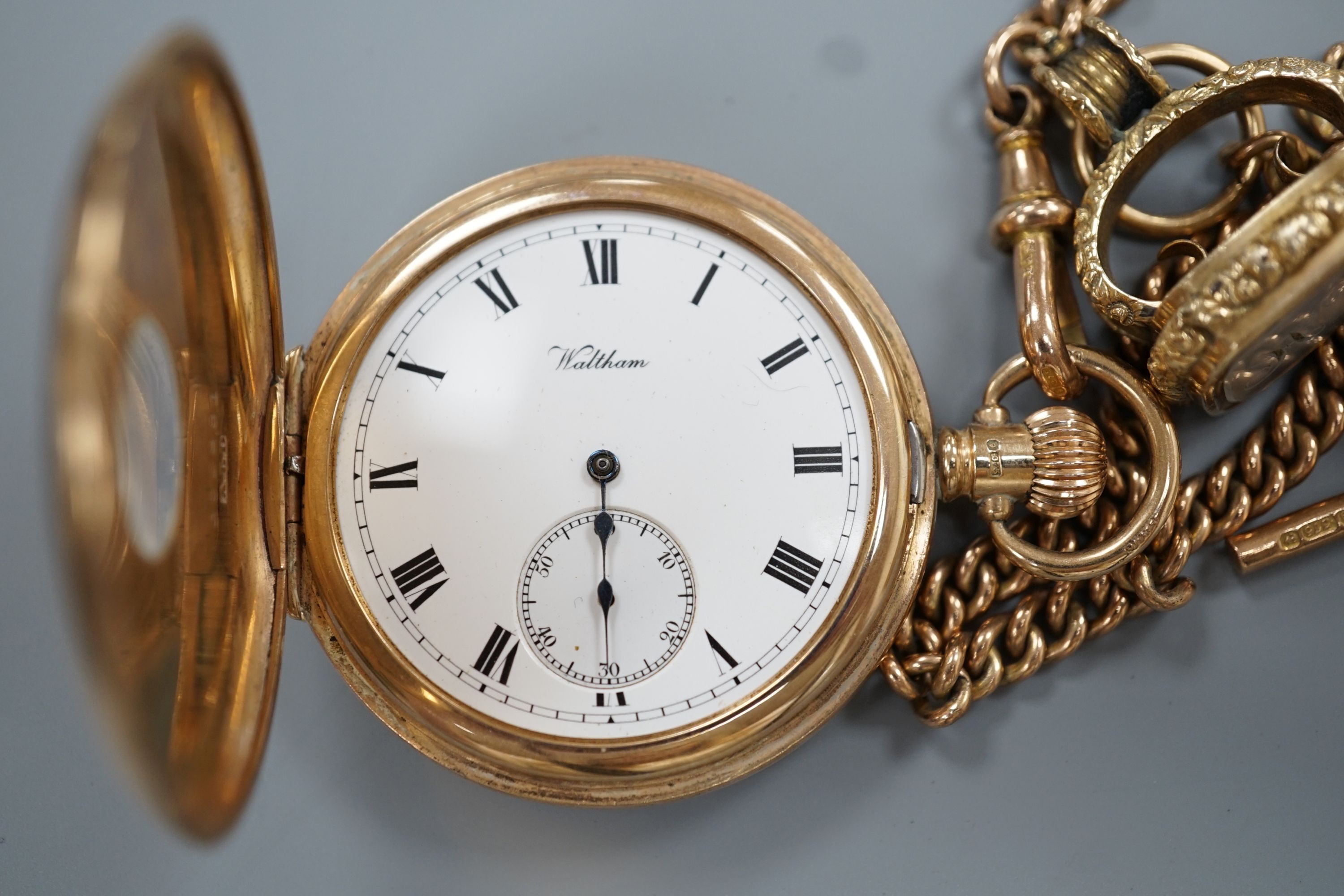 A 1920's 9ct gold Waltham keyless half hunter pocket watch, on a 9ct gold albert, hung with a Victorian yellow metal overlaid and carnelian set fob seal